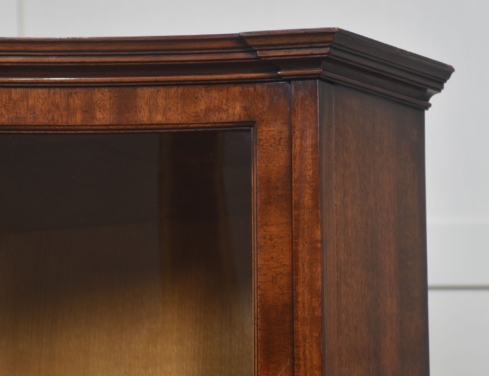 A large mahogany glazed display cabinet featuring an arched central section with glass doors, flame mahogany drawer fronts, and oval inlaid cupboard panels. View XVI