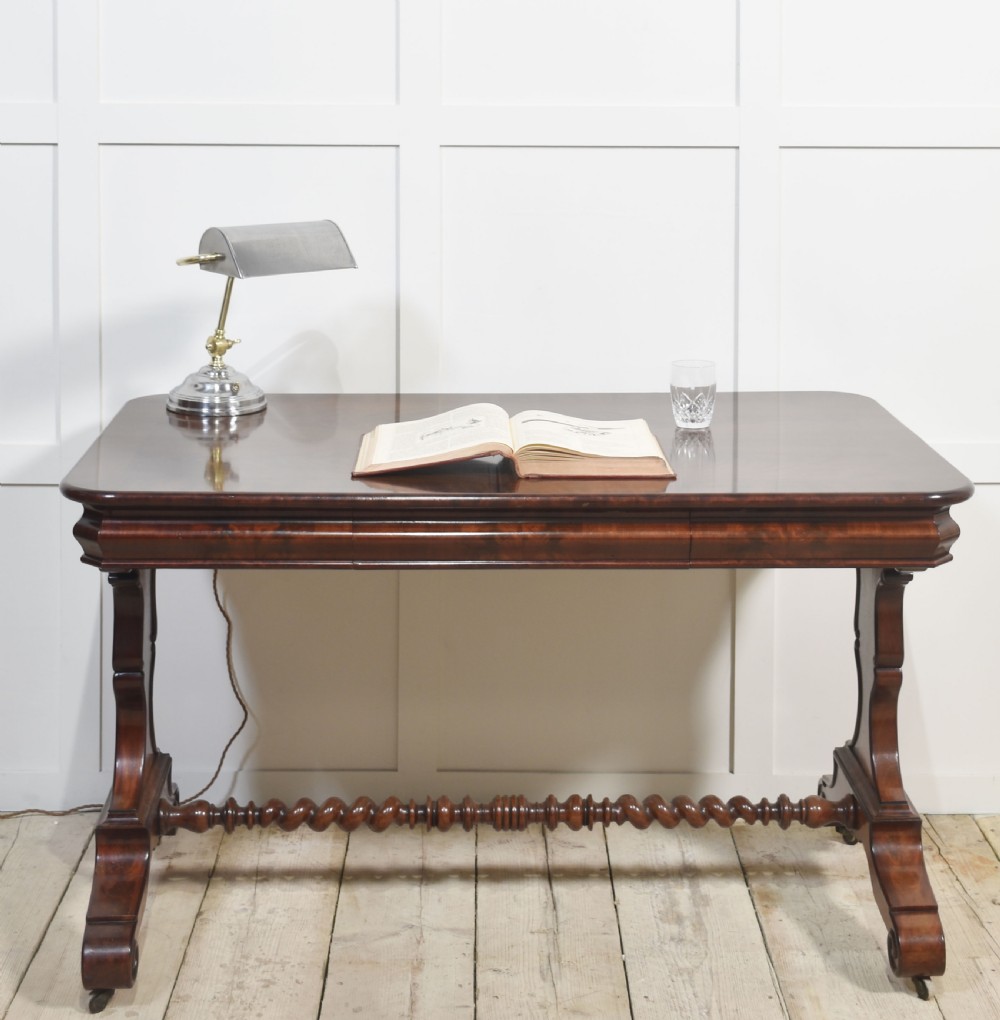 A Victorian mahogany centre table featuring a polished rectangular top with rounded corners, trestle end supports, a spiral-turned stretcher, and scroll feet on castors. View III
