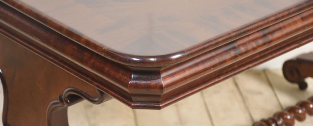A Victorian mahogany centre table featuring a polished rectangular top with rounded corners, trestle end supports, a spiral-turned stretcher, and scroll feet on castors. View V