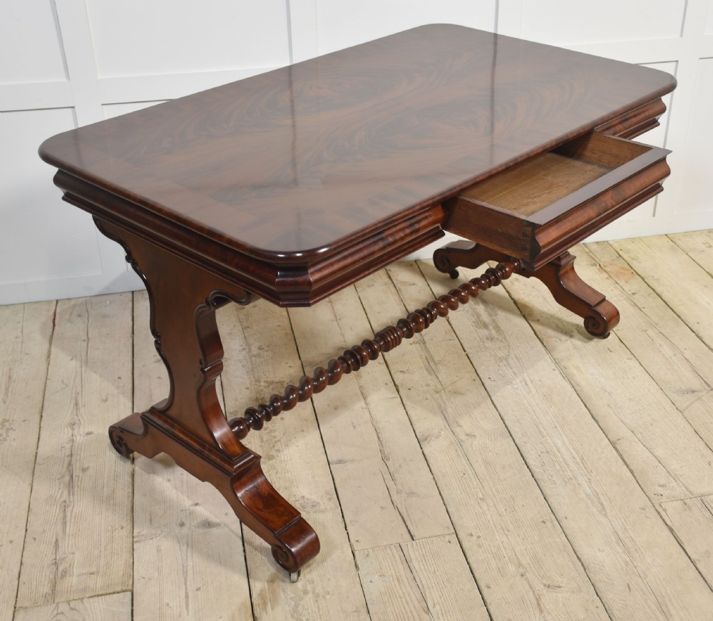 A Victorian mahogany centre table featuring a polished rectangular top with rounded corners, trestle end supports, a spiral-turned stretcher, and scroll feet on castors. View VIII