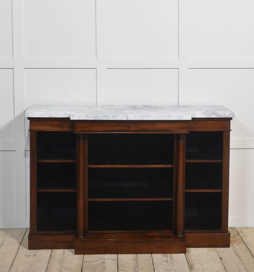 A 19th-century rosewood breakfront open bookcase featuring a pale marble top surface and decorative turned columns flanking open shelves filled with books. View V