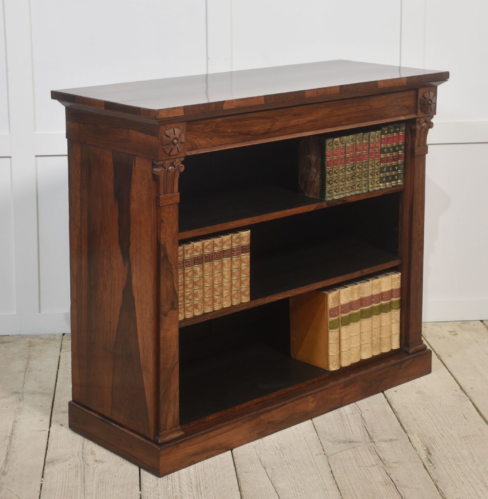 A 19th-century rosewood open bookcase featuring three open shelves, carved corner rosettes, pilasters, and a solid plinth base. View VII