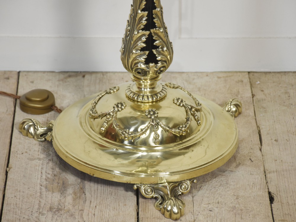 An antique brass telescopic standard lamp featuring a reeded ebonised shaft, ornate cast scroll base, and a pleated cream fabric shade. View VII