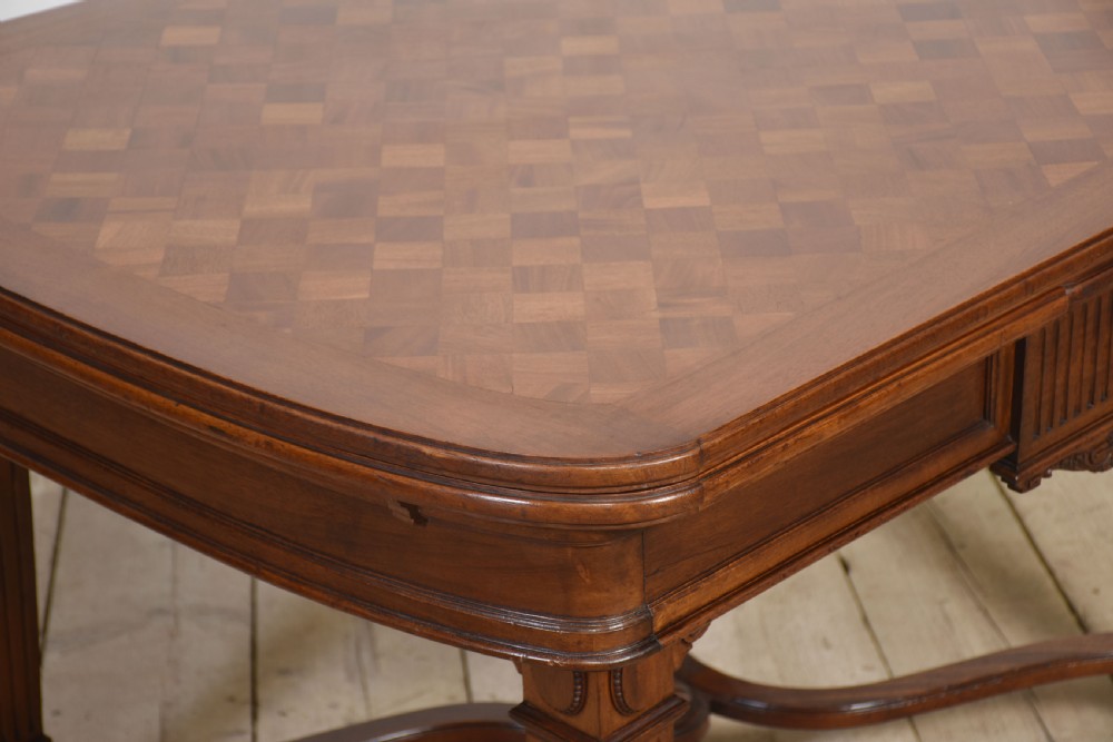 A walnut parquetry draw-leaf dining table featuring a geometric diamond-pattern top, fluted tapered legs, and a curved stretcher base. View II