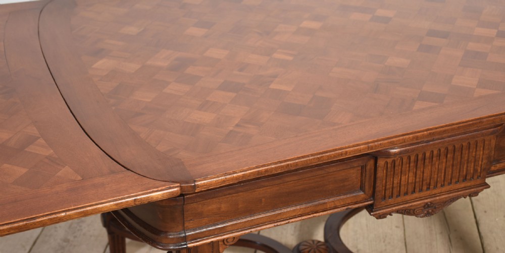 A walnut parquetry draw-leaf dining table featuring a geometric diamond-pattern top, fluted tapered legs, and a curved stretcher base. View VIII