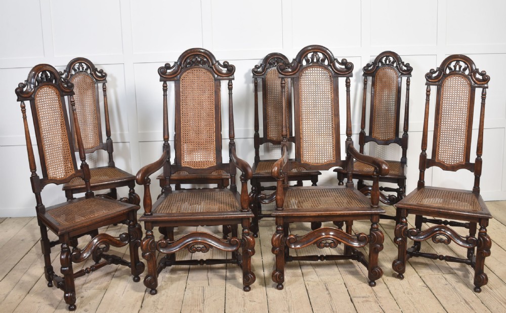 Set of eight carved dark oak high-back dining chairs with woven cane backrests and seats, comprising two armchairs and six side chairs.