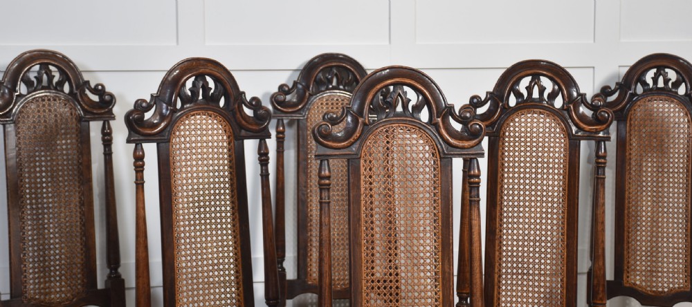 Set of eight carved dark oak high-back dining chairs with woven cane backrests and seats, comprising two armchairs and six side chairs. View VII