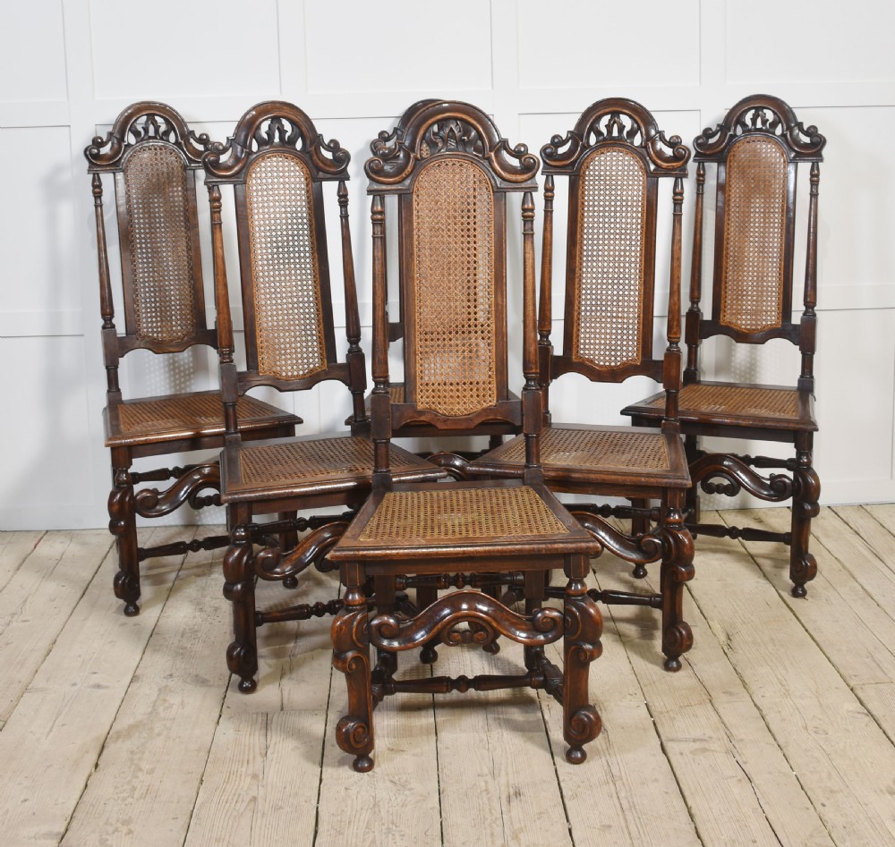Set of eight carved dark oak high-back dining chairs with woven cane backrests and seats, comprising two armchairs and six side chairs. View VIII