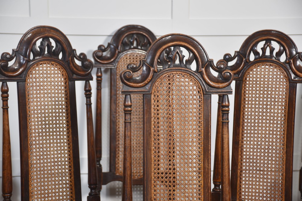 Set of eight carved dark oak high-back dining chairs with woven cane backrests and seats, comprising two armchairs and six side chairs. View IX