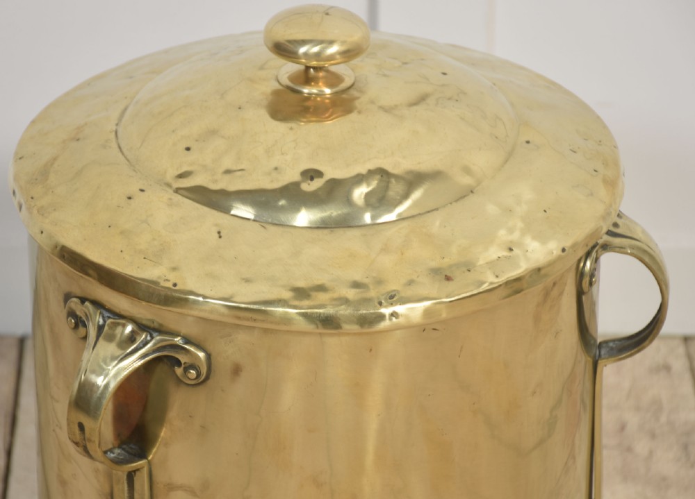 A cylindrical polished brass Art Nouveau coal bin featuring stylised cast feet, side handles, and a domed lid with a finial handle. View IV