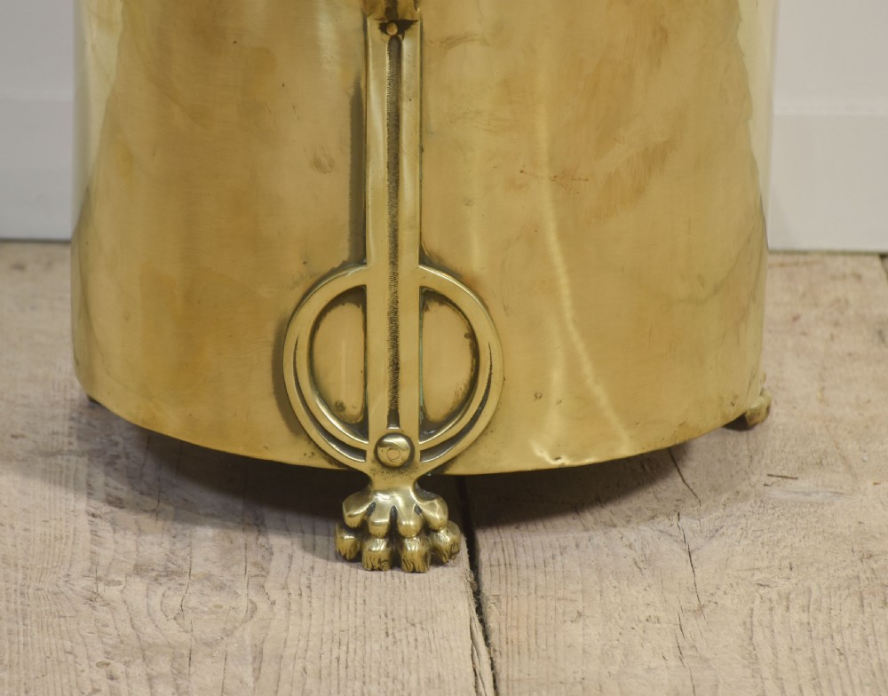 A cylindrical polished brass Art Nouveau coal bin featuring stylised cast feet, side handles, and a domed lid with a finial handle. View VI