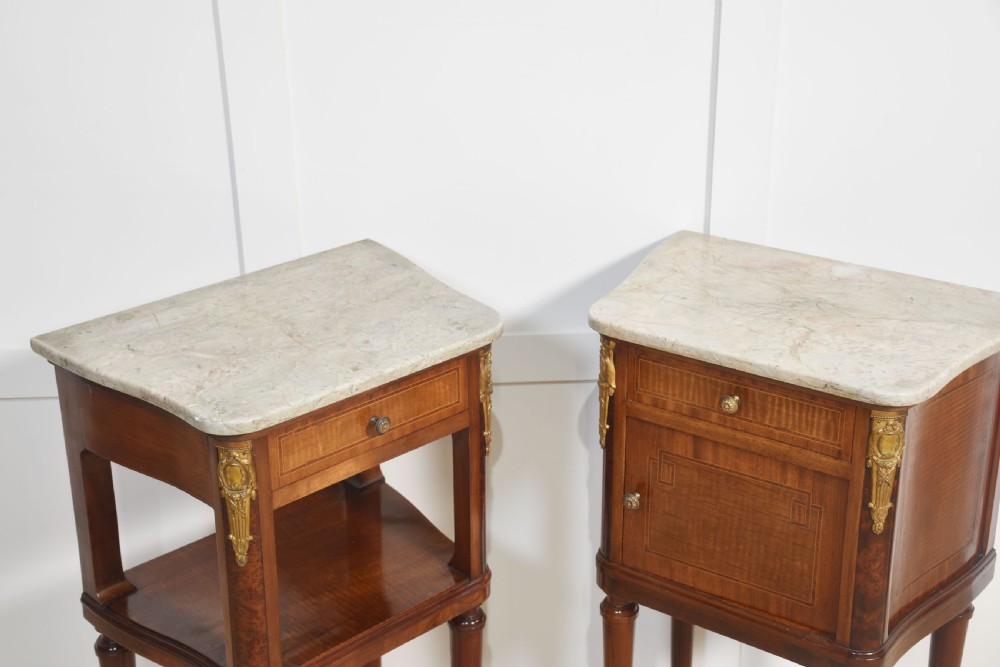 A pair of French Louis XVI style mahogany bedside cabinets featuring pale marble tops, gilt metal corner mounts, single drawers, and slender turned legs. View VI