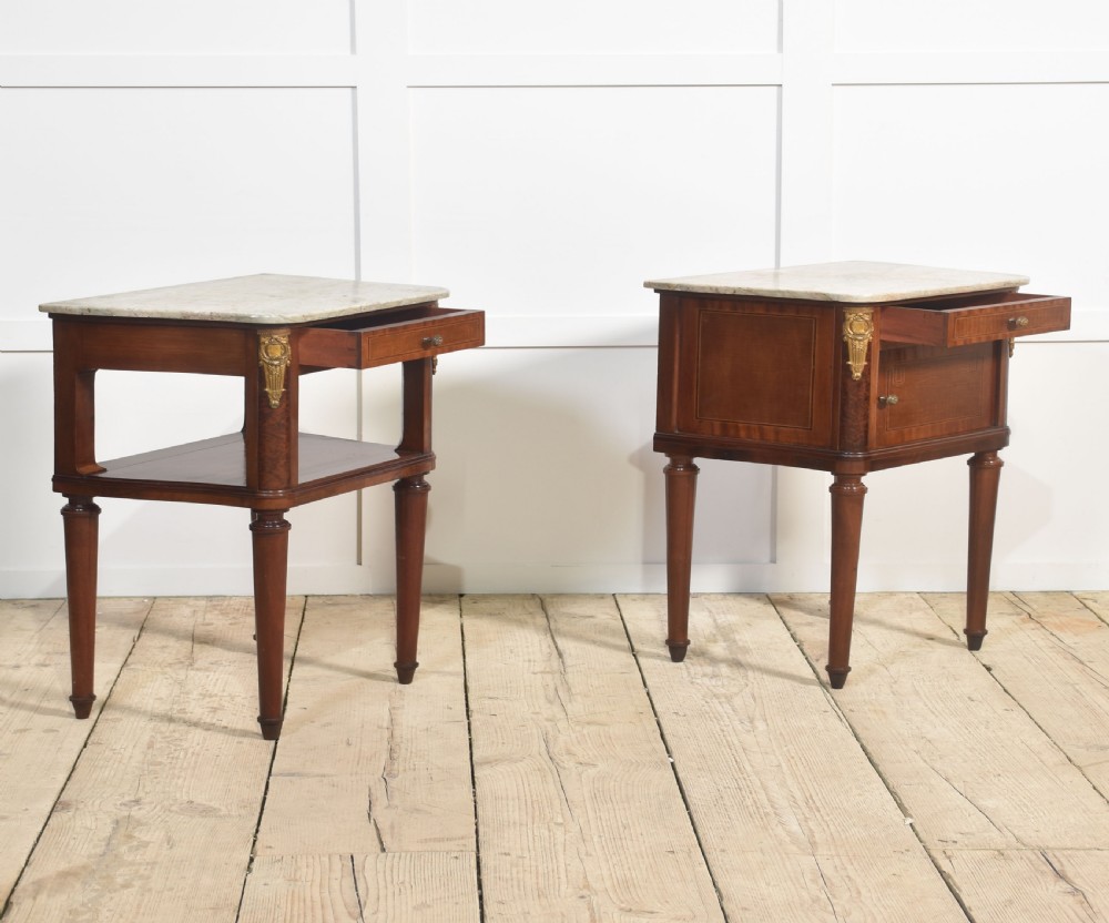 A pair of French Louis XVI style mahogany bedside cabinets featuring pale marble tops, gilt metal corner mounts, single drawers, and slender turned legs. View XI