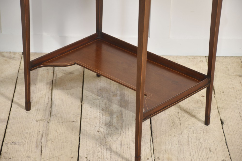 An antique mahogany dressing table with an integrated shield-shaped mirror, twin trinket drawers with brass galleries, a central drawer, and tall tapered legs. View X