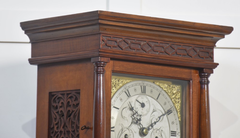A tall, slim antique mahogany grandmother clock with an engraved brass and silvered dial, decorative columns, and a polished flame mahogany case. View III