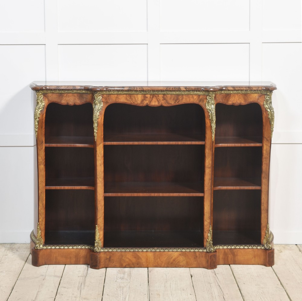 An antique figured walnut breakfront open bookcase featuring three shelf compartments and ornamental gilt metal mounts along the frieze and pilasters. View II