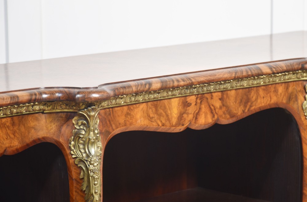 An antique figured walnut breakfront open bookcase featuring three shelf compartments and ornamental gilt metal mounts along the frieze and pilasters. View VIII