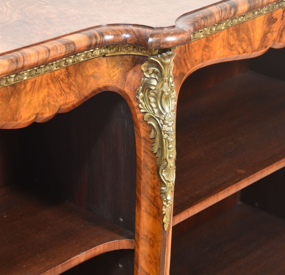 An antique figured walnut breakfront open bookcase featuring three shelf compartments and ornamental gilt metal mounts along the frieze and pilasters. View X