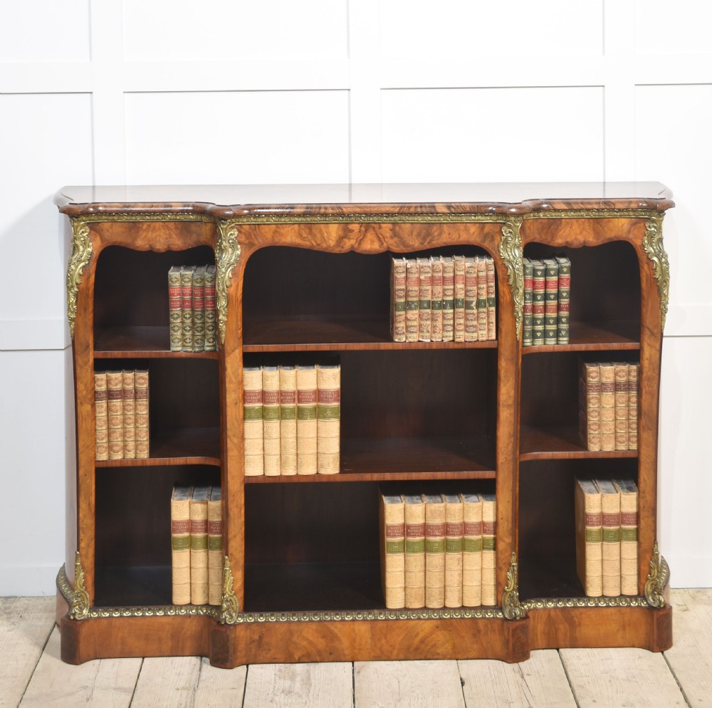An antique figured walnut breakfront open bookcase featuring three shelf compartments and ornamental gilt metal mounts along the frieze and pilasters. View XI