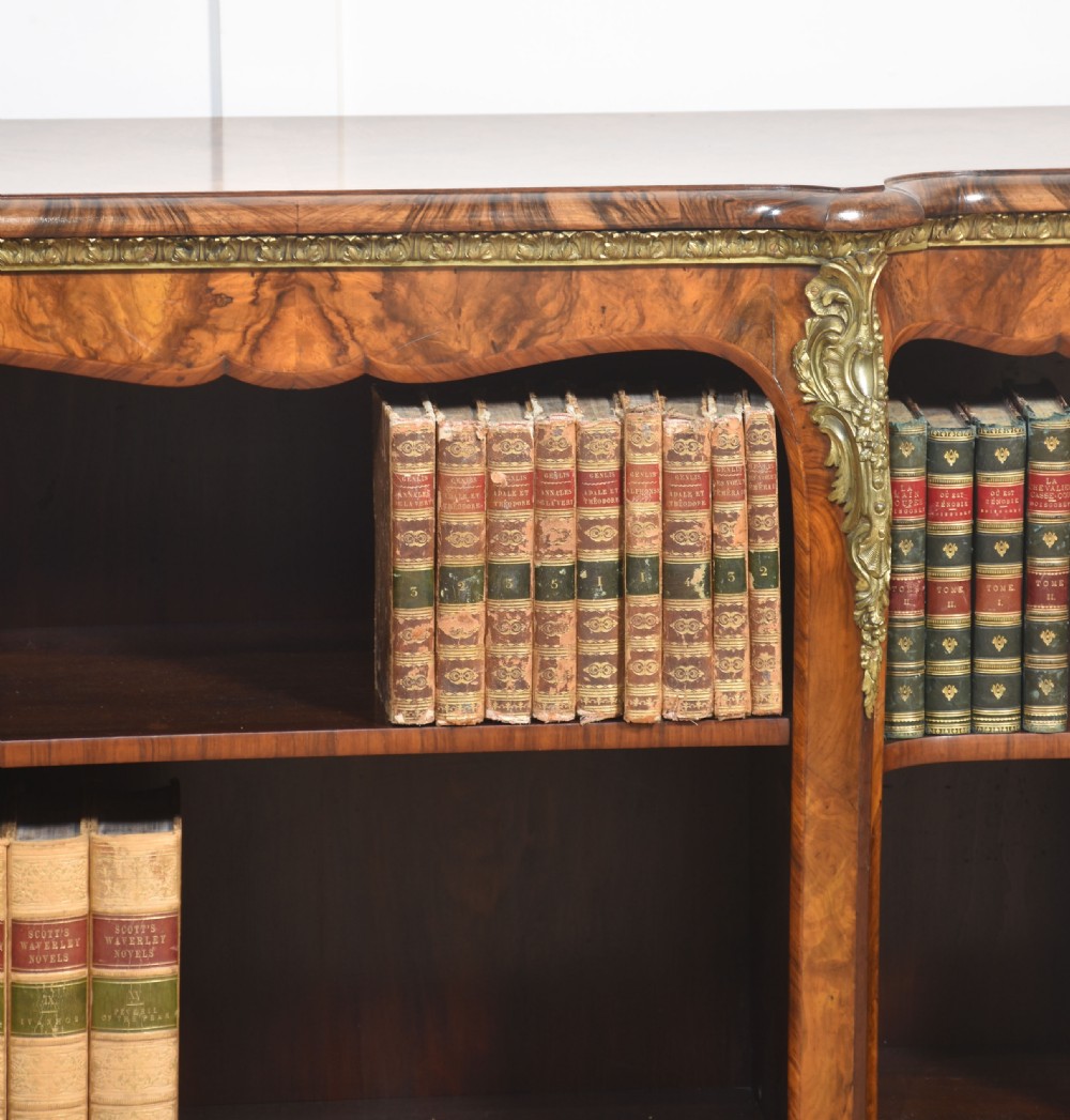 An antique figured walnut breakfront open bookcase featuring three shelf compartments and ornamental gilt metal mounts along the frieze and pilasters. View XII