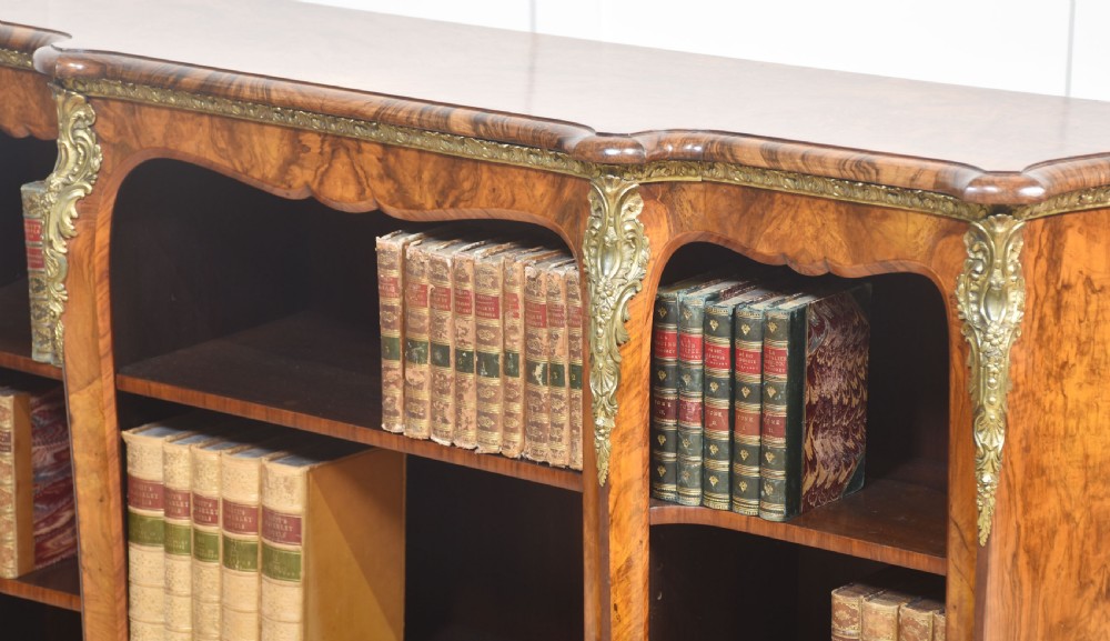 An antique figured walnut breakfront open bookcase featuring three shelf compartments and ornamental gilt metal mounts along the frieze and pilasters. View XVI