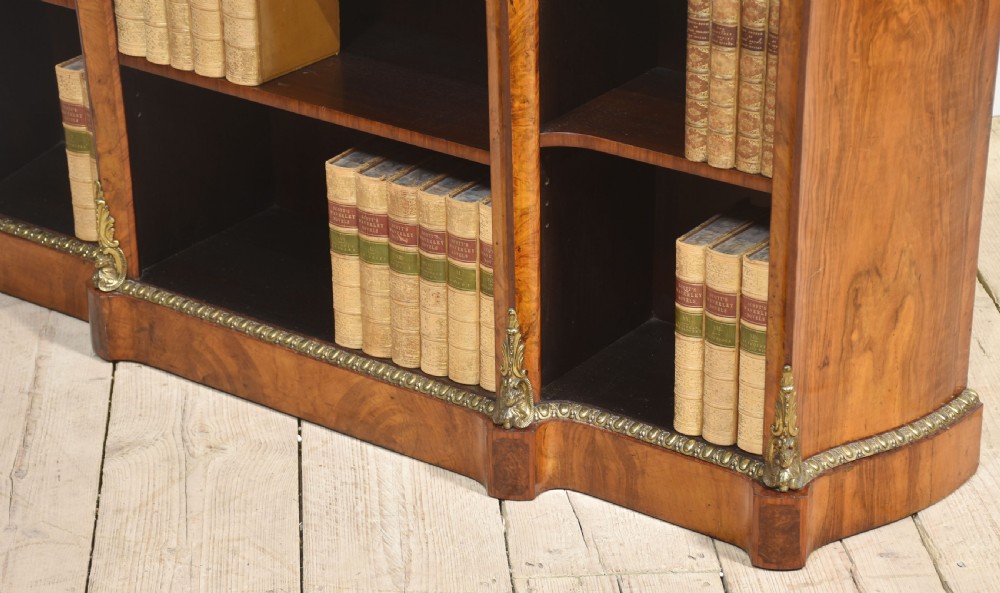 An antique figured walnut breakfront open bookcase featuring three shelf compartments and ornamental gilt metal mounts along the frieze and pilasters. View XVII
