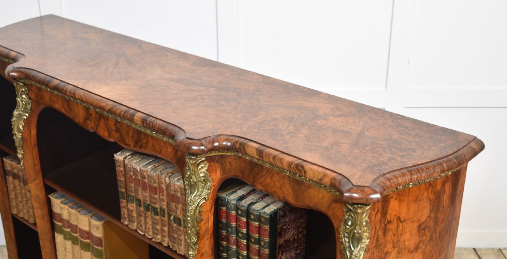 An antique figured walnut breakfront open bookcase featuring three shelf compartments and ornamental gilt metal mounts along the frieze and pilasters. View XVIII