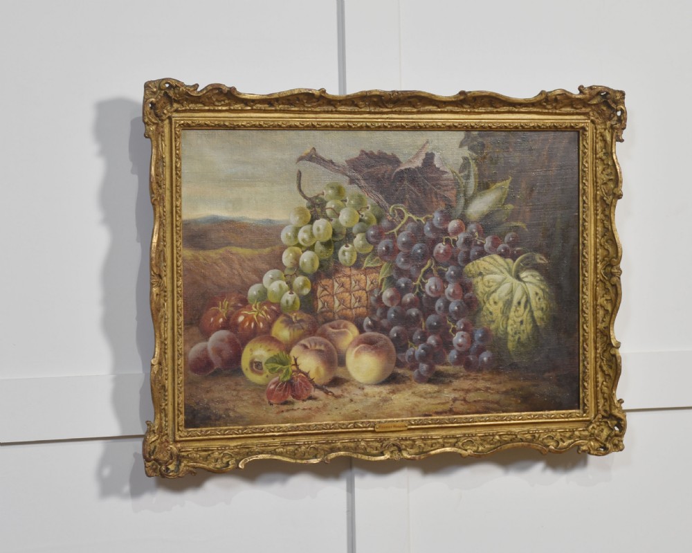 An antique oil on canvas still life painting depicting an arrangement of grapes, peaches, and melons within an ornate gilded frame. View IV