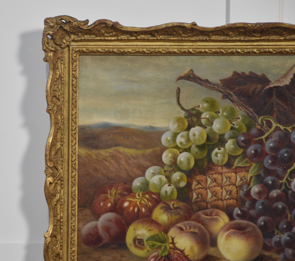 An antique oil on canvas still life painting depicting an arrangement of grapes, peaches, and melons within an ornate gilded frame. View V