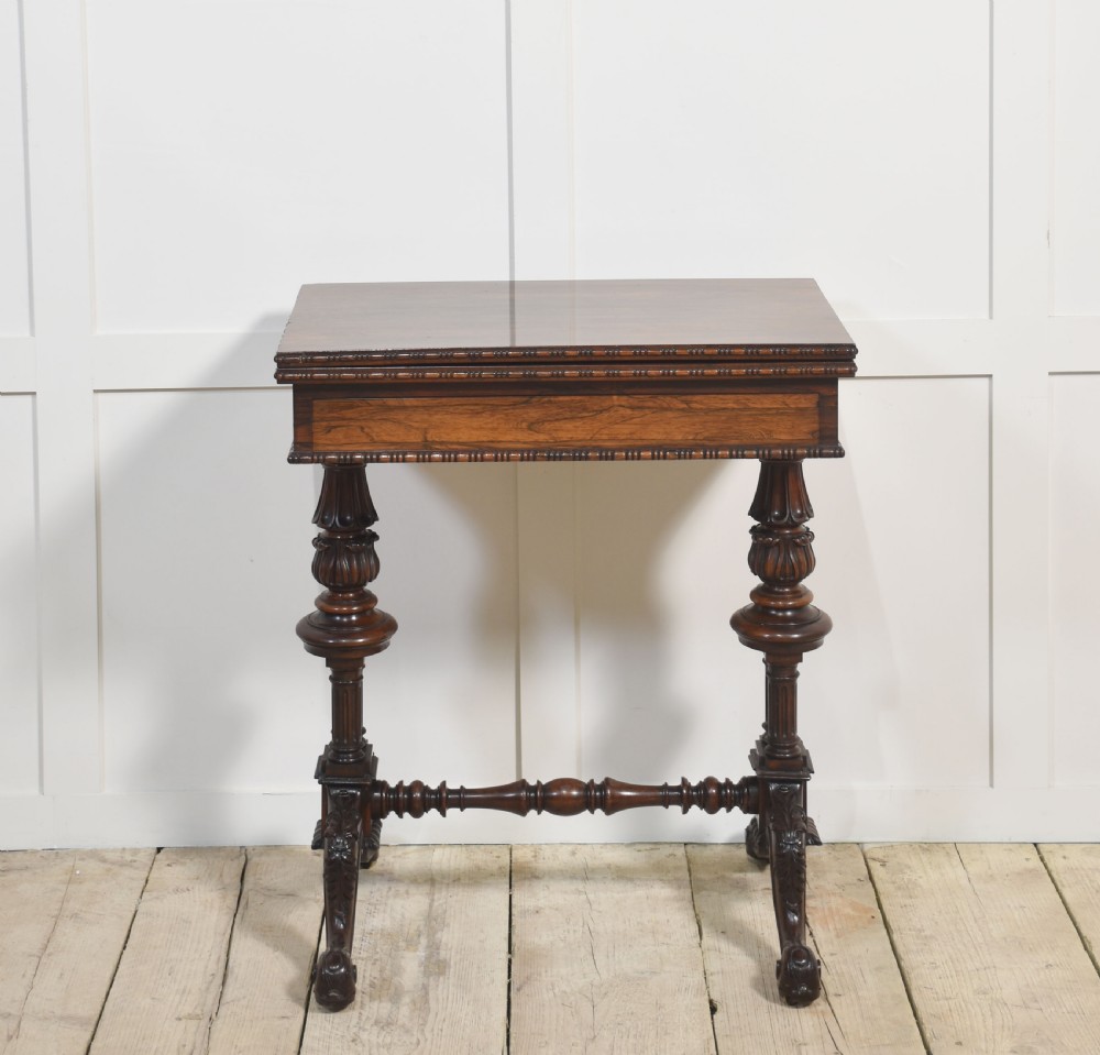 A 19th-century rosewood fold-over card table featuring turned legs, carved pedestals, and a stretcher base.