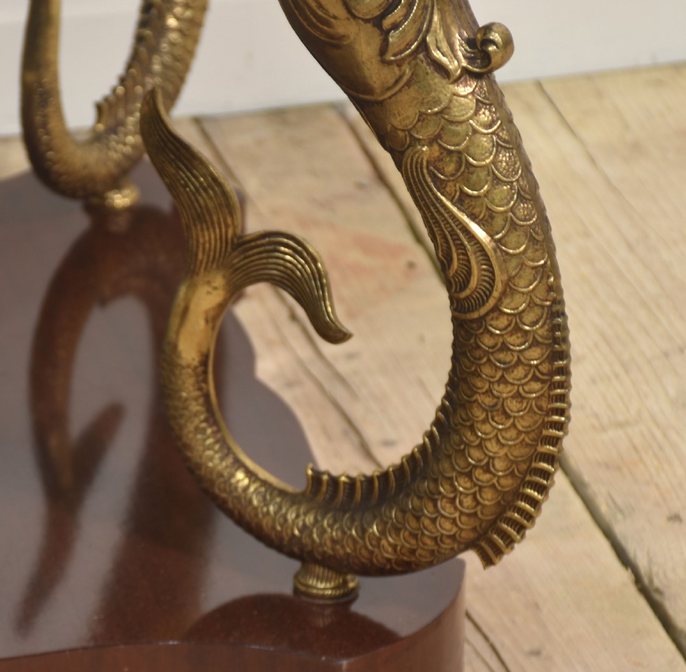 A circular white marble coffee table supported by four cast gilt metal dolphin legs on a dark wooden base. View II