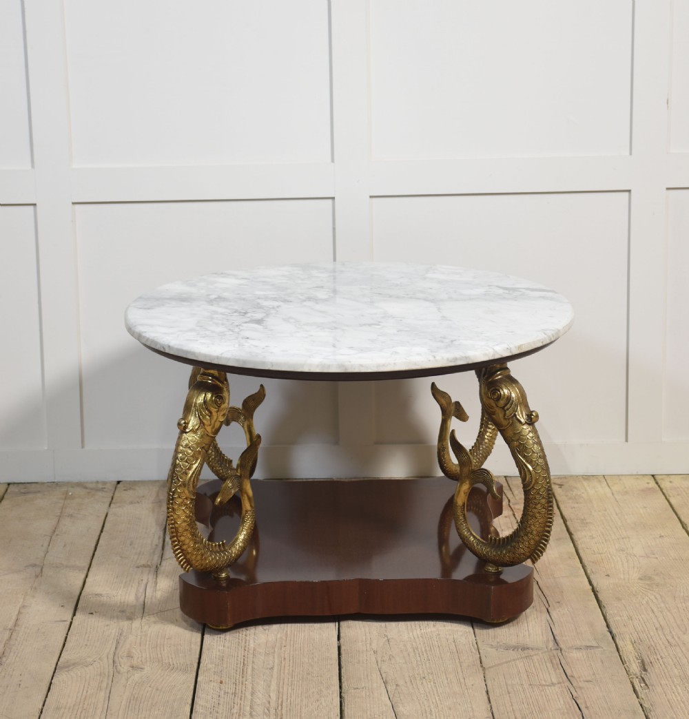 A circular white marble coffee table supported by four cast gilt metal dolphin legs on a dark wooden base. View III