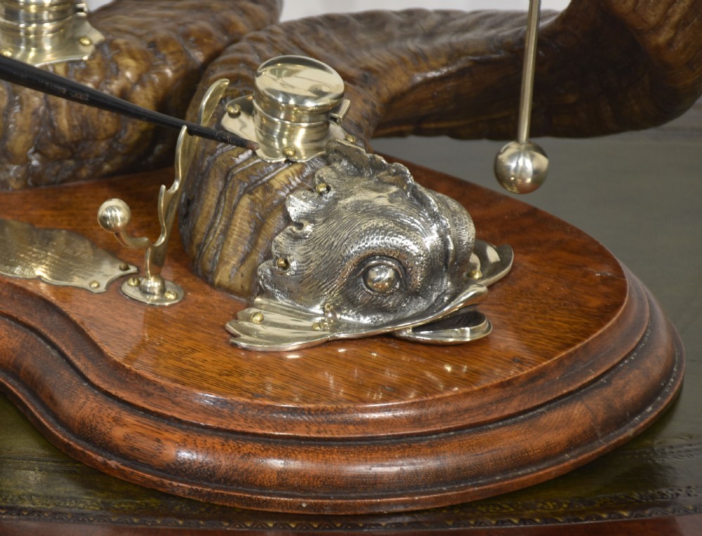 A 19th-century desk inkstand constructed from two curved natural horns, fitted with silvered dolphin-head mounts, inkwells, and a central suspended brass bell on a polished wooden base. View VII