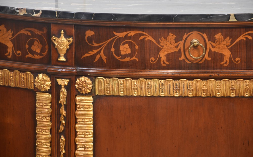 An Italian Neoclassical mahogany bowfront cabinet featuring a black marble top, marquetry frieze with foliate motifs, and carved parcel gilt trims. View III