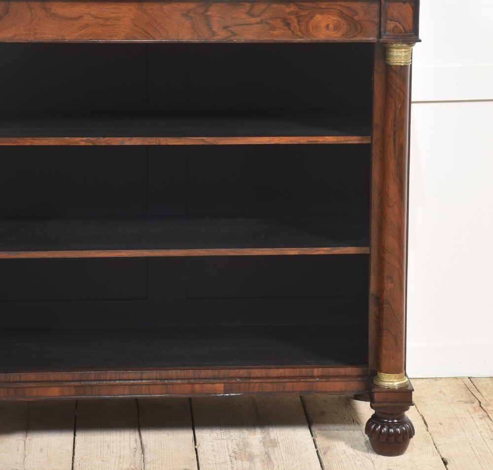 A 19th-century rosewood open bookcase featuring brass pillar supports, a tiered upper shelf gallery, open lower shelves, and turned feet. View VII