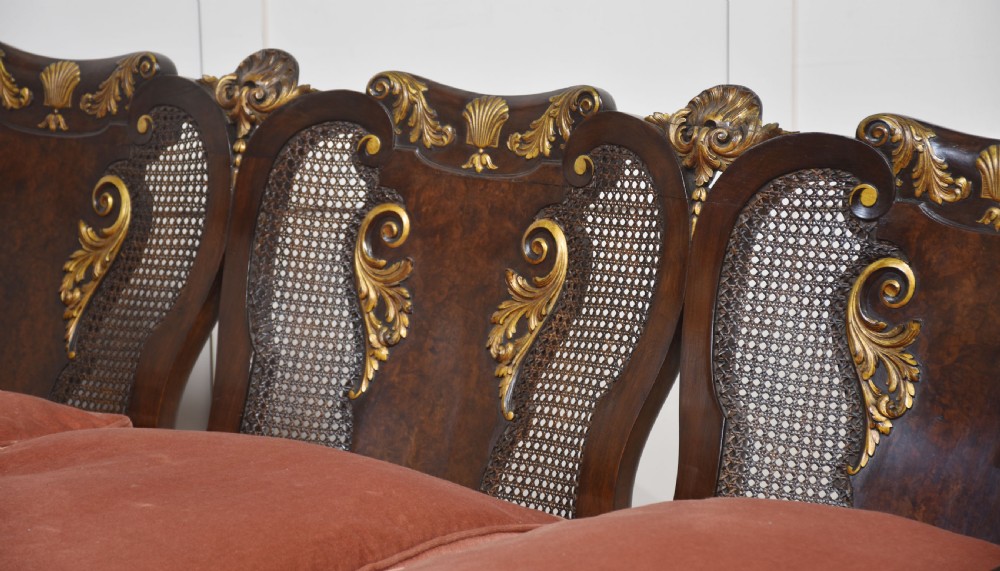 A three-seater carved walnut sofa featuring caned panels, parcel-gilt shell carved details, cabriole legs, and three rose-pink velvet seat cushions. View VI