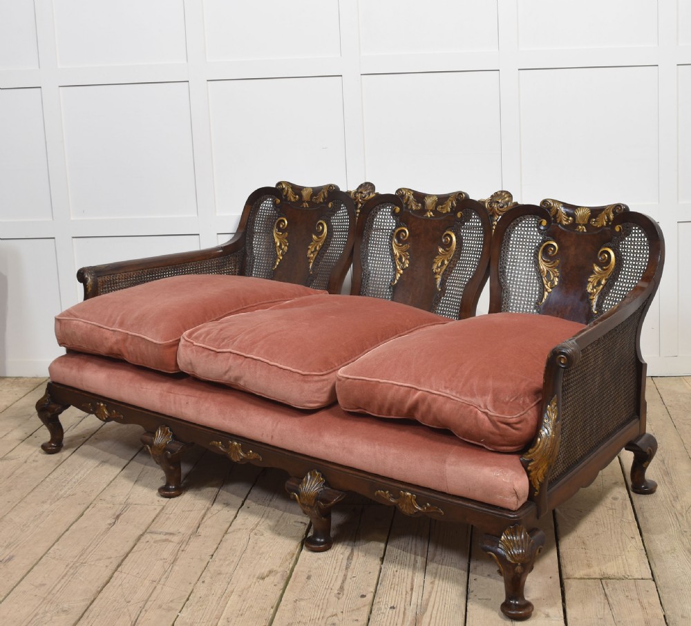 A three-seater carved walnut sofa featuring caned panels, parcel-gilt shell carved details, cabriole legs, and three rose-pink velvet seat cushions. View VII
