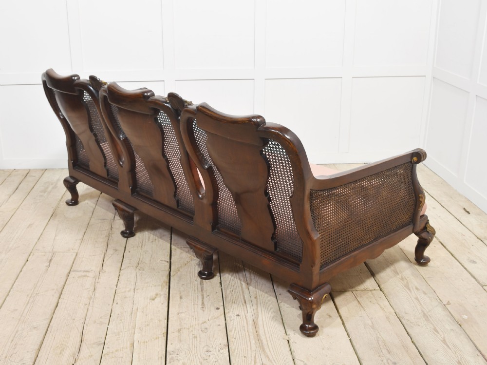 A three-seater carved walnut sofa featuring caned panels, parcel-gilt shell carved details, cabriole legs, and three rose-pink velvet seat cushions. View XI