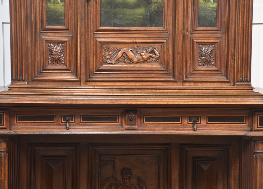 A two-tier dark walnut cabinet on stand featuring classical relief carvings, painted figural panels, fluted columns, and a top balustrade gallery. View VII