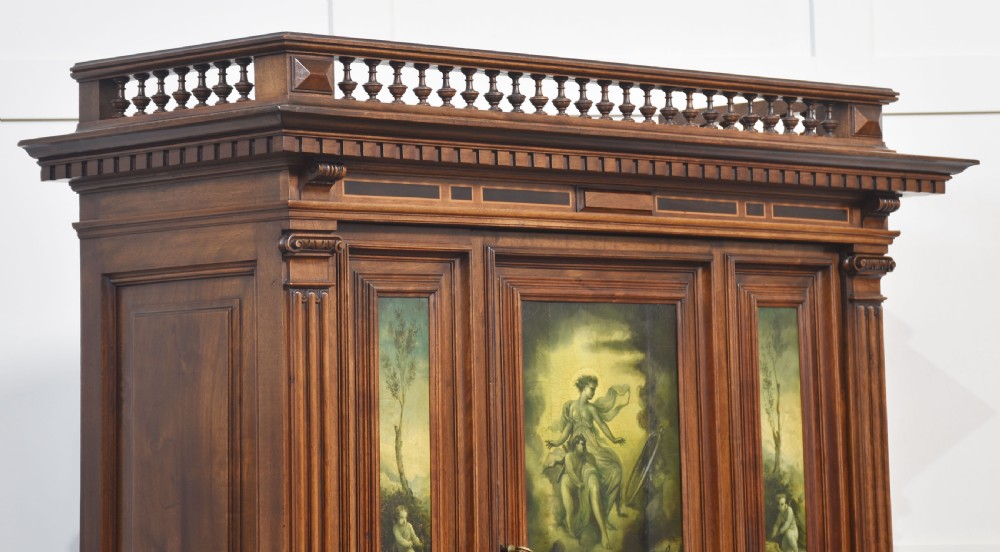 A two-tier dark walnut cabinet on stand featuring classical relief carvings, painted figural panels, fluted columns, and a top balustrade gallery. View VIII