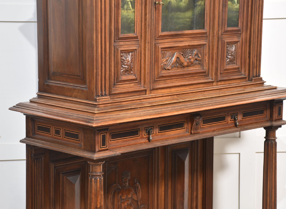 A two-tier dark walnut cabinet on stand featuring classical relief carvings, painted figural panels, fluted columns, and a top balustrade gallery. View XI