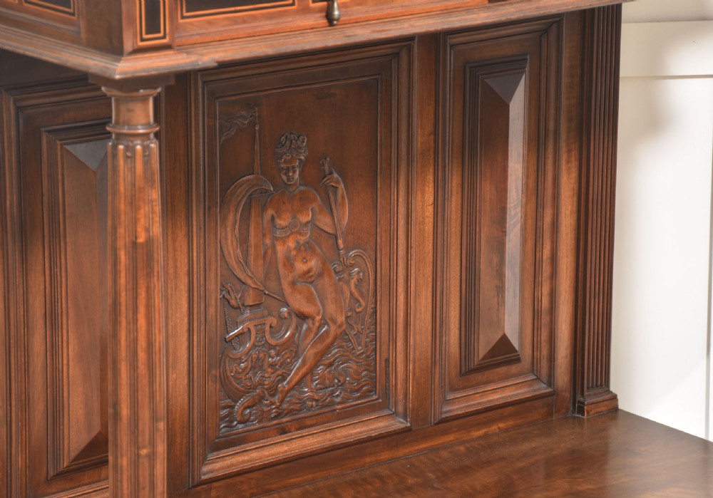 A two-tier dark walnut cabinet on stand featuring classical relief carvings, painted figural panels, fluted columns, and a top balustrade gallery. View XII