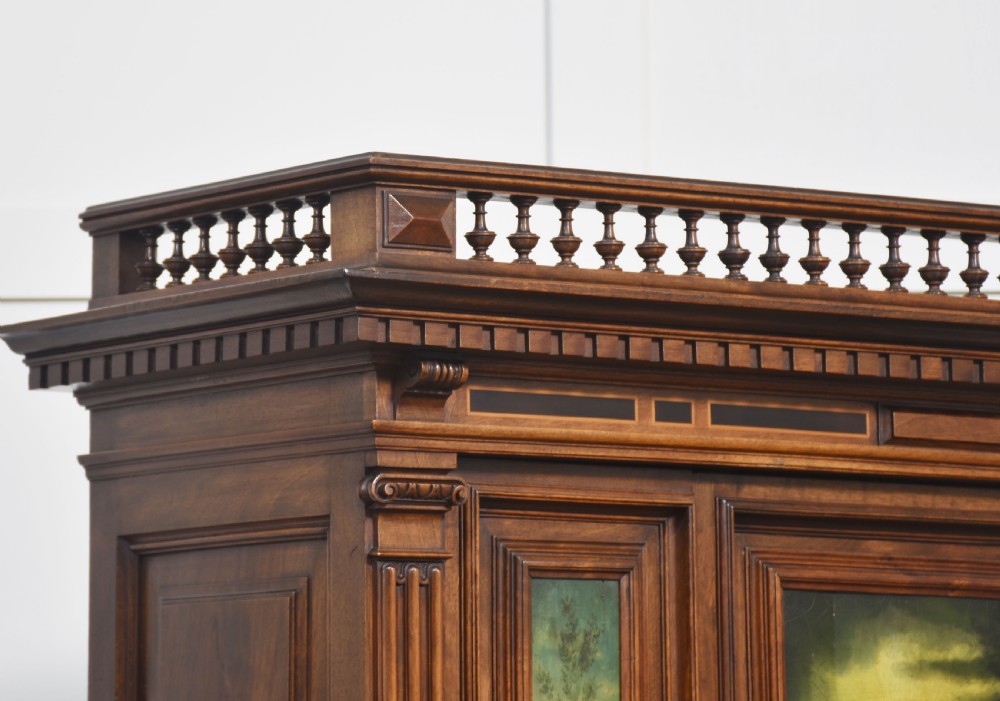 A two-tier dark walnut cabinet on stand featuring classical relief carvings, painted figural panels, fluted columns, and a top balustrade gallery. View XIII