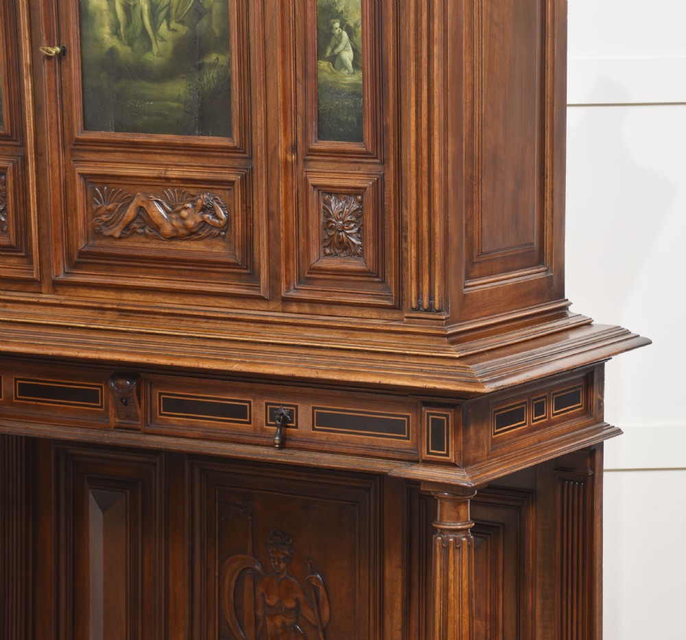 A two-tier dark walnut cabinet on stand featuring classical relief carvings, painted figural panels, fluted columns, and a top balustrade gallery. View XV