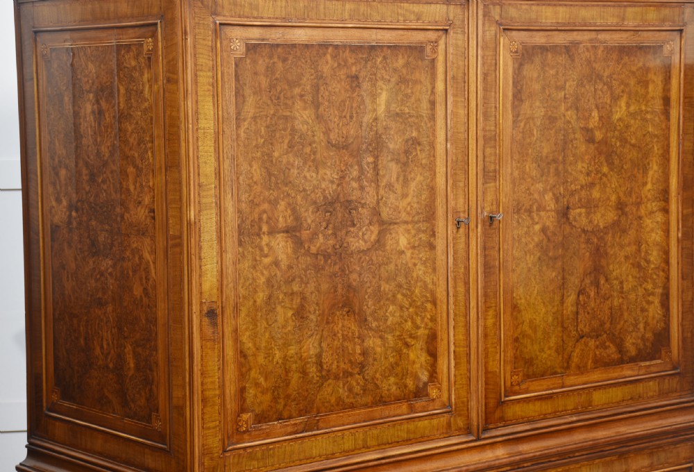 A two-section figured walnut press cupboard featuring twin panelled doors with crossbanded borders and bracket feet with a central star inlay. View XI