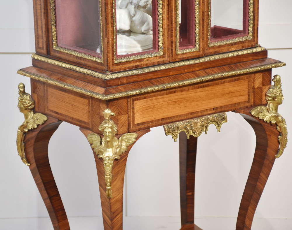 An antique kingwood glazed display cabinet elevated on cabriole legs with decorative gilt bronze mounts and a burgundy fabric interior. View VI