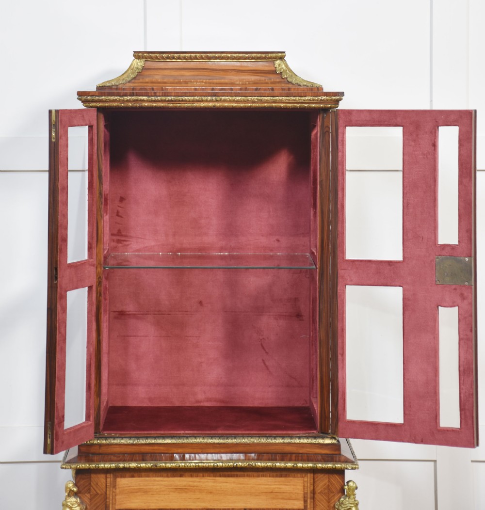 An antique kingwood glazed display cabinet elevated on cabriole legs with decorative gilt bronze mounts and a burgundy fabric interior. View X