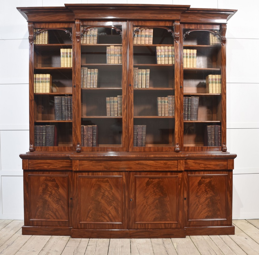 A 19th-century mahogany breakfront bookcase featuring glazed upper doors with adjustable shelves above a base with flame mahogany panelled doors.
