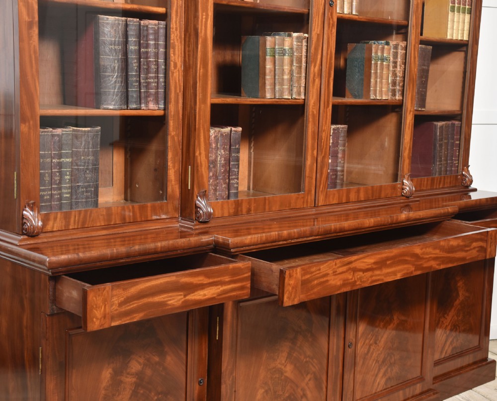 A 19th-century mahogany breakfront bookcase featuring glazed upper doors with adjustable shelves above a base with flame mahogany panelled doors. View X