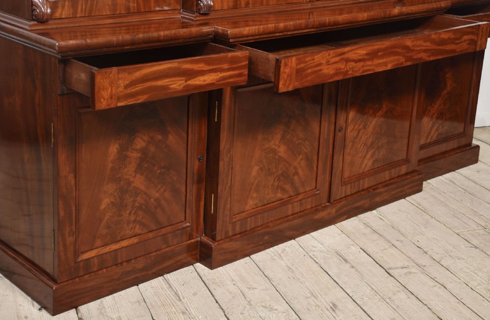 A 19th-century mahogany breakfront bookcase featuring glazed upper doors with adjustable shelves above a base with flame mahogany panelled doors. View XI